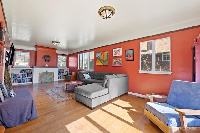 living room with visible vents, baseboards, wood finished floors, and crown molding