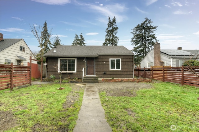 bungalow with a front lawn, a fenced backyard, and roof with shingles