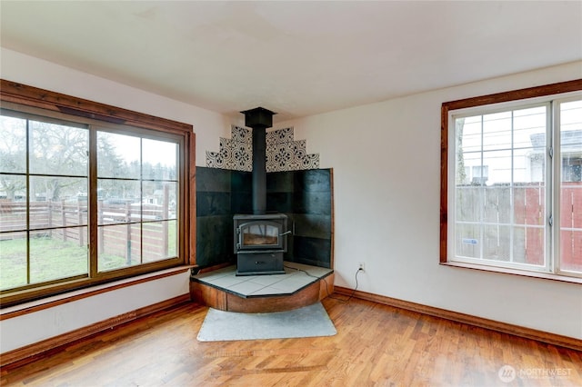 living room featuring a wood stove, wood finished floors, and baseboards