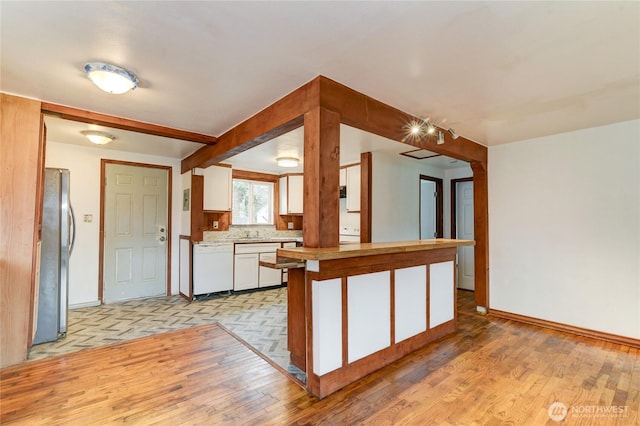 kitchen with backsplash, white cabinetry, freestanding refrigerator, light wood finished floors, and dishwasher