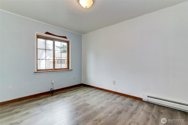 empty room with baseboards, baseboard heating, and wood finished floors