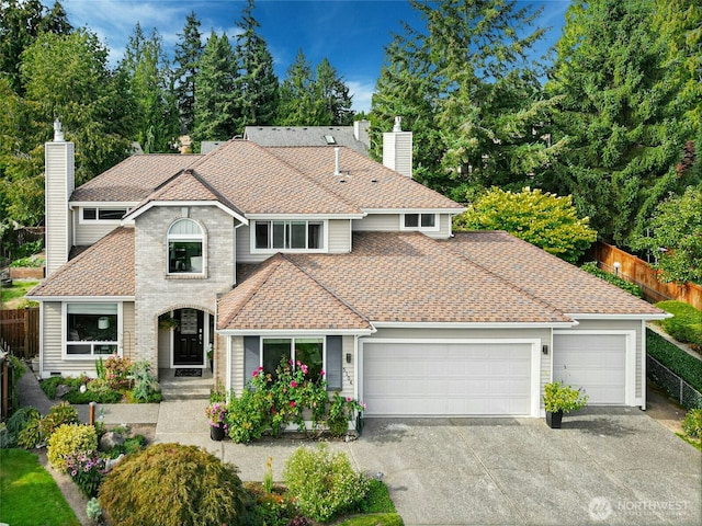 view of front facade featuring fence, roof with shingles, driveway, a chimney, and a garage