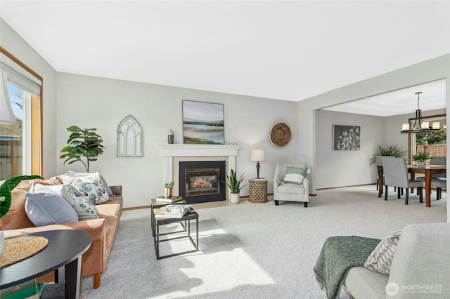 carpeted living room featuring a notable chandelier, a fireplace with flush hearth, baseboards, and a wealth of natural light