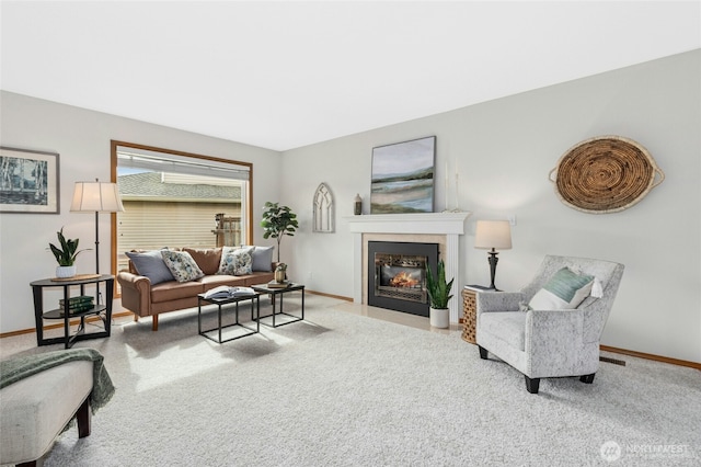 carpeted living room featuring baseboards and a fireplace with flush hearth