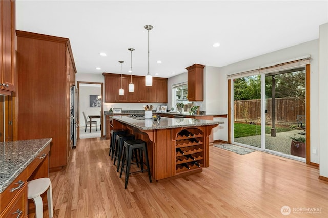 kitchen with light wood finished floors, a kitchen island, a breakfast bar, a sink, and stainless steel appliances