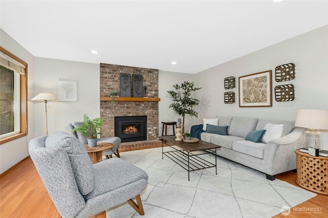 living room featuring recessed lighting, a brick fireplace, and wood finished floors