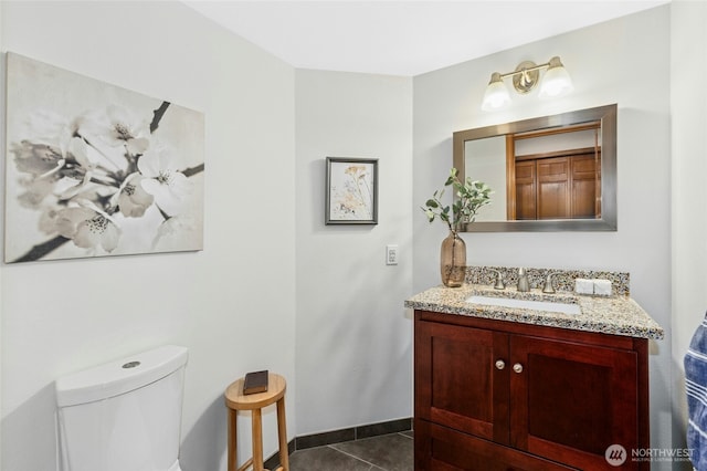 bathroom with tile patterned flooring, toilet, vanity, and baseboards