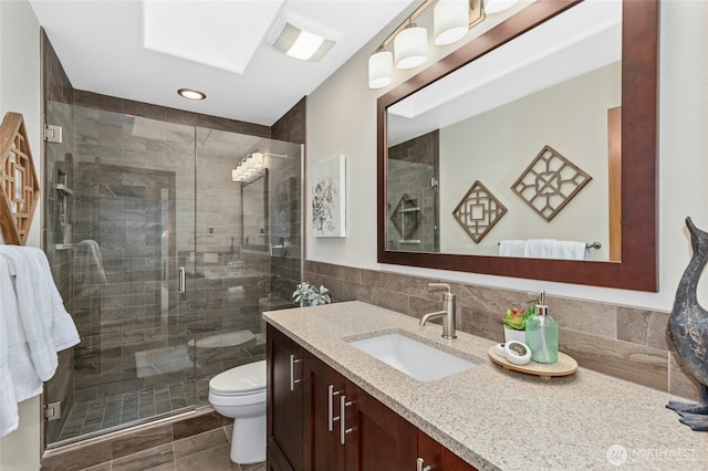 full bath with vanity, a skylight, a stall shower, tile walls, and toilet