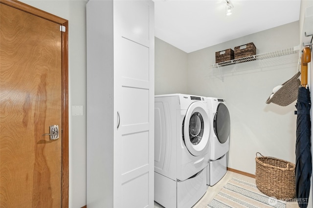 clothes washing area with laundry area, separate washer and dryer, and baseboards