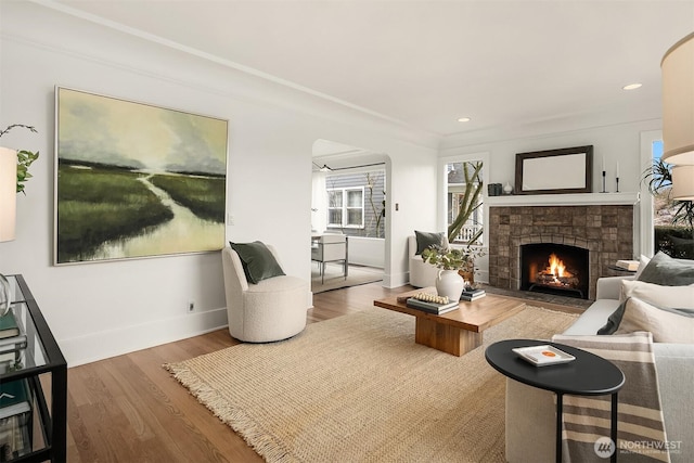 living room featuring recessed lighting, a fireplace, baseboards, and wood finished floors