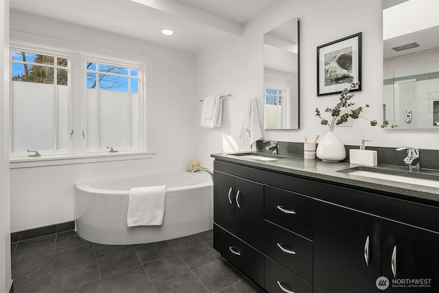 full bathroom featuring a sink, a bathtub, double vanity, and tile patterned floors