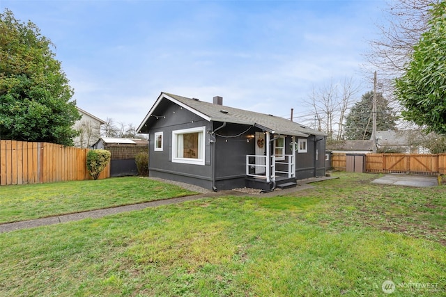 back of house with a gate, a yard, a fenced backyard, and a chimney