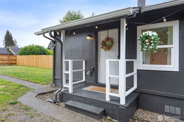 doorway to property featuring visible vents, a lawn, and fence