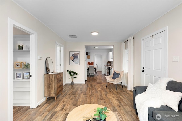 living room with visible vents, baseboards, and wood finished floors