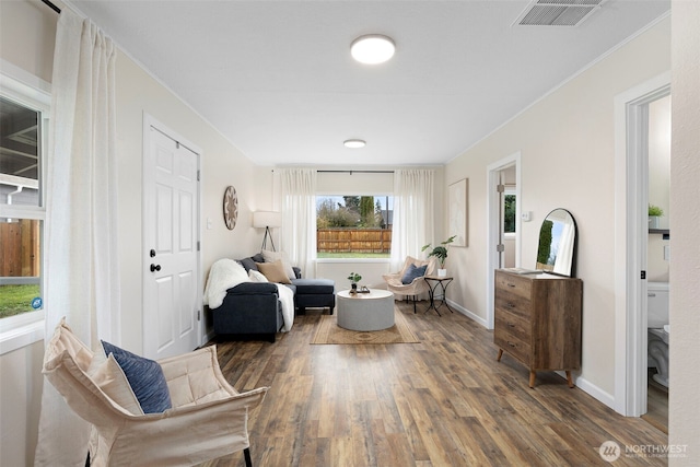 sitting room with visible vents, crown molding, baseboards, and wood finished floors