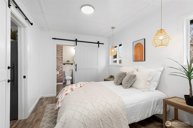 bedroom with ensuite bathroom, baseboards, dark wood-type flooring, and a barn door