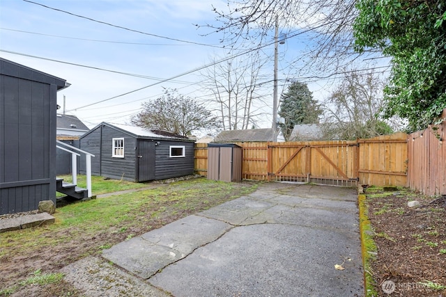 view of yard with a storage shed, a gate, fence, and an outdoor structure