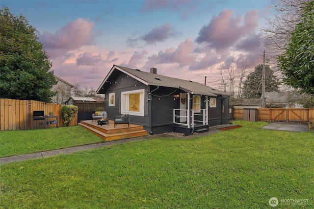 back of property with a wooden deck, a lawn, a fenced backyard, and a gate