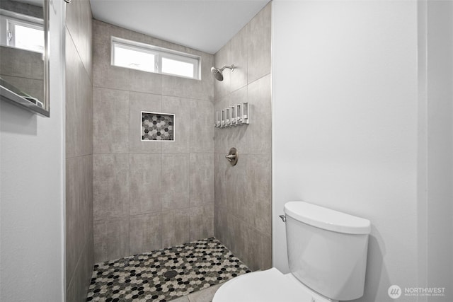 full bathroom featuring toilet and a tile shower