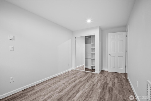 unfurnished bedroom with visible vents, wood finished floors, recessed lighting, a closet, and baseboards