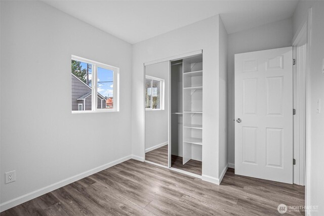 unfurnished bedroom with a closet, baseboards, and wood finished floors