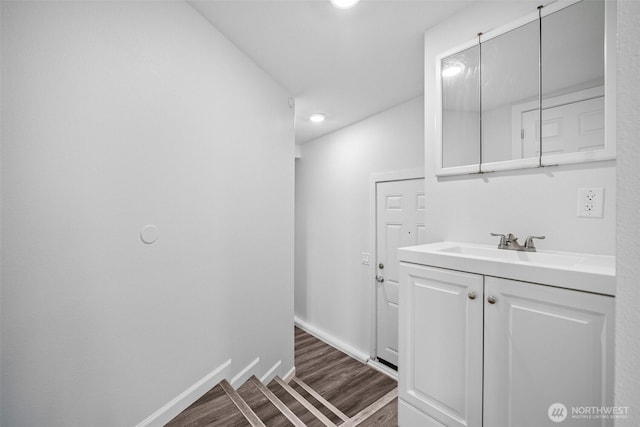 laundry area with dark wood-type flooring, baseboards, and a sink