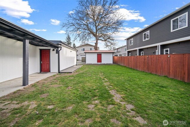 view of yard with a storage shed, an outdoor structure, and fence