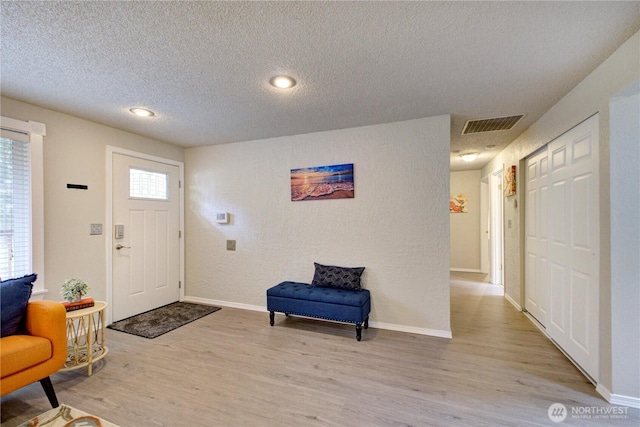 entrance foyer featuring light wood finished floors, visible vents, a textured ceiling, and baseboards