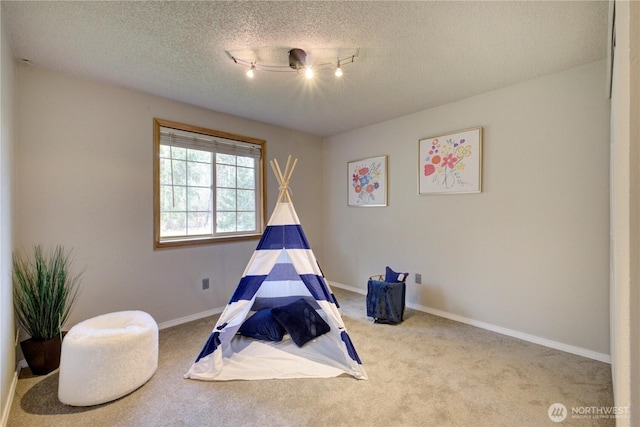 recreation room with baseboards, carpet floors, and a textured ceiling