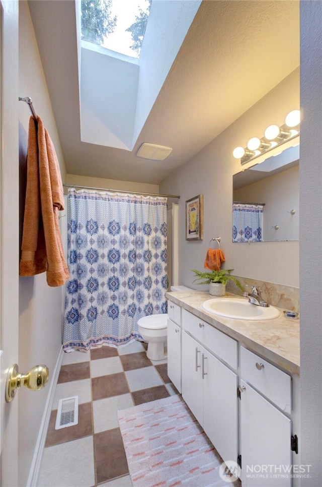 bathroom with visible vents, toilet, a skylight, tile patterned floors, and vanity