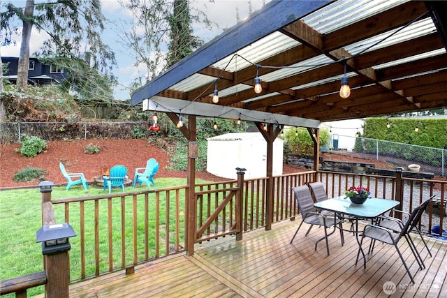 wooden terrace with a storage unit, an outbuilding, outdoor dining space, a fenced backyard, and a yard