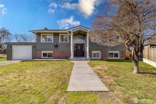 bi-level home with brick siding, an attached garage, a front lawn, and fence