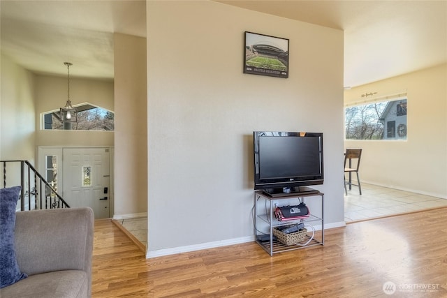 living area featuring baseboards, high vaulted ceiling, wood finished floors, and stairs