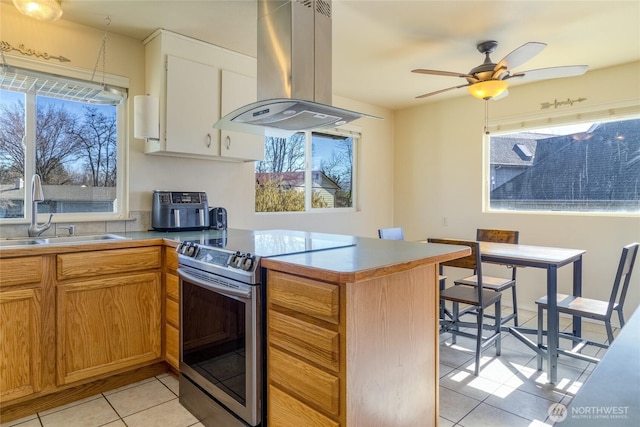 kitchen with a peninsula, light tile patterned flooring, a sink, stainless steel range with electric stovetop, and island range hood