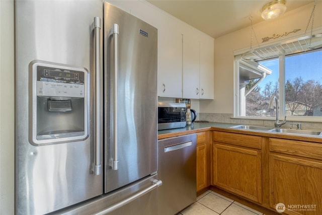 kitchen featuring a sink, appliances with stainless steel finishes, light tile patterned flooring, and brown cabinetry