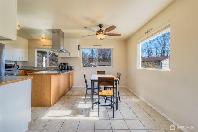 kitchen featuring white cabinetry, light tile patterned floors, a wealth of natural light, and island range hood