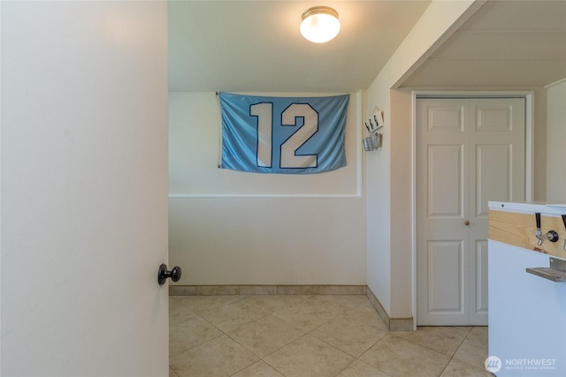 corridor featuring light tile patterned flooring and baseboards