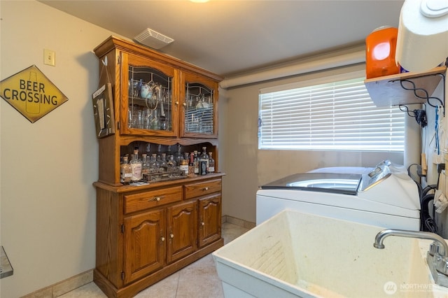 washroom with washing machine and clothes dryer, a sink, baseboards, and light tile patterned flooring