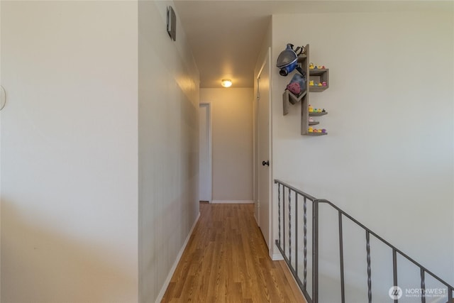 corridor featuring light wood-style flooring and baseboards