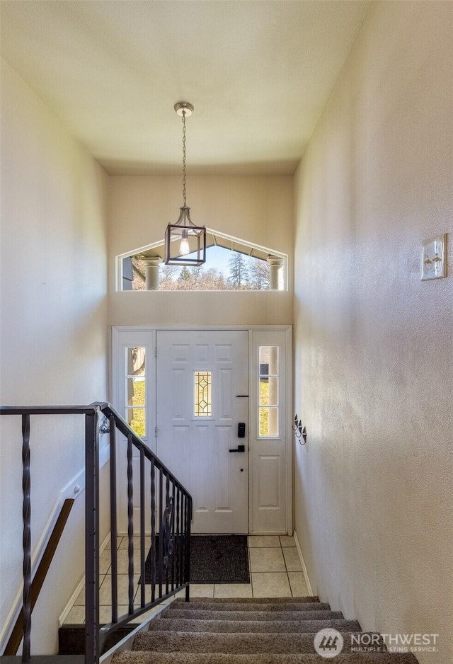 foyer with tile patterned flooring, a healthy amount of sunlight, high vaulted ceiling, and baseboards