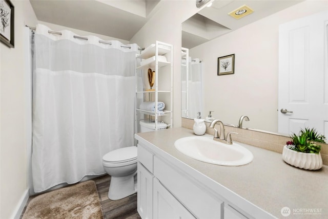 bathroom featuring curtained shower, toilet, wood finished floors, and vanity