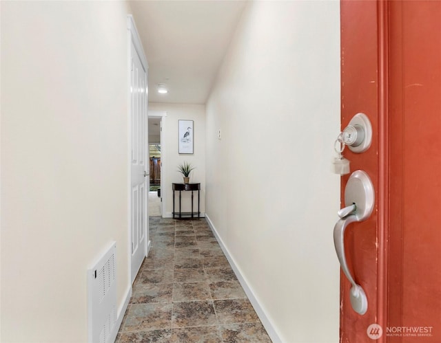 corridor featuring visible vents, stone finish floor, and baseboards