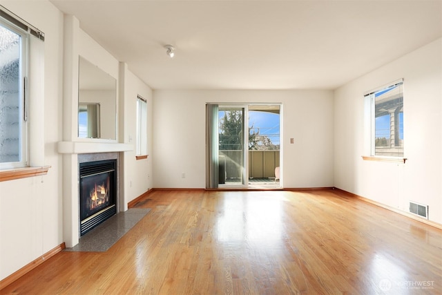 unfurnished living room featuring visible vents, a fireplace, baseboards, and wood finished floors