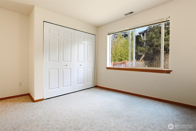 unfurnished bedroom featuring a closet, baseboards, visible vents, and carpet flooring