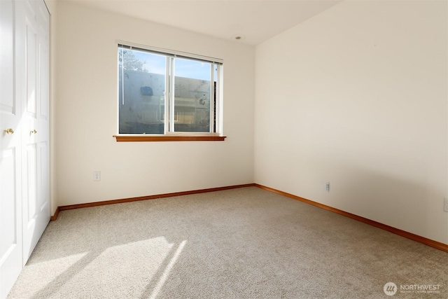 spare room featuring baseboards and light carpet