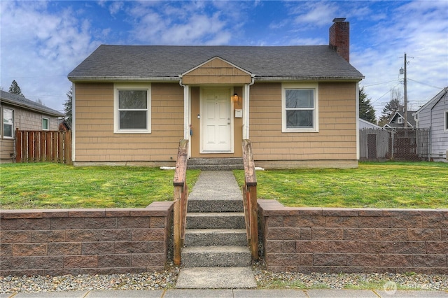 bungalow-style home with a shingled roof, a front lawn, fence, and a chimney