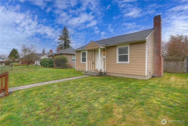 view of front facade featuring a chimney, a front lawn, and fence