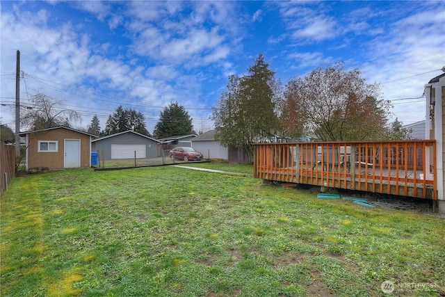 view of yard featuring a garage, a deck, an outdoor structure, and fence