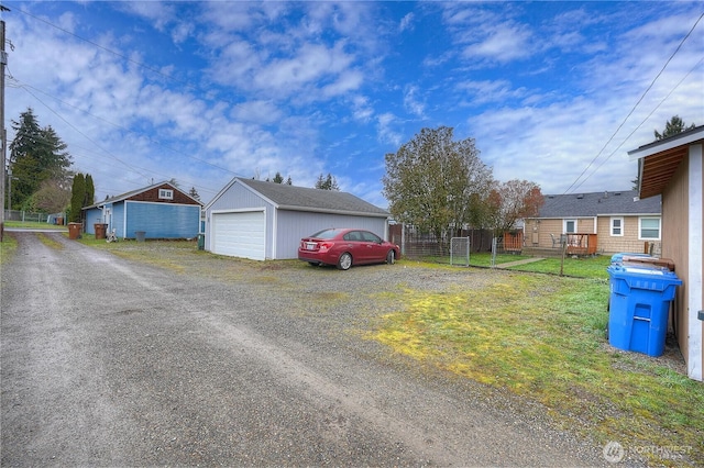 view of front of home featuring an outbuilding, driveway, a detached garage, and fence