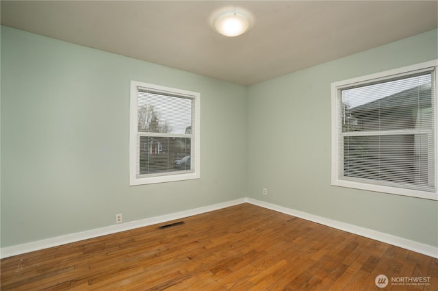 spare room with visible vents, baseboards, and hardwood / wood-style floors